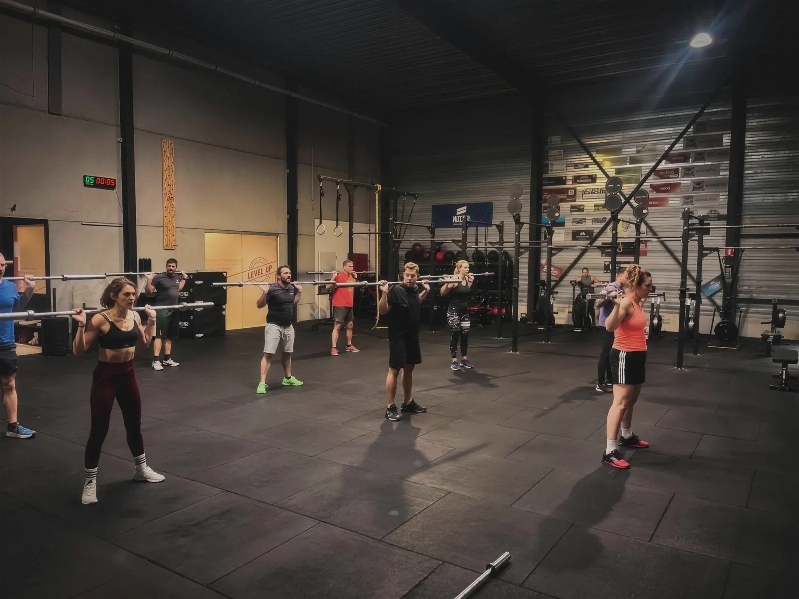 Groepsles oefent samen de barbell-techniek op de trainingsvloer